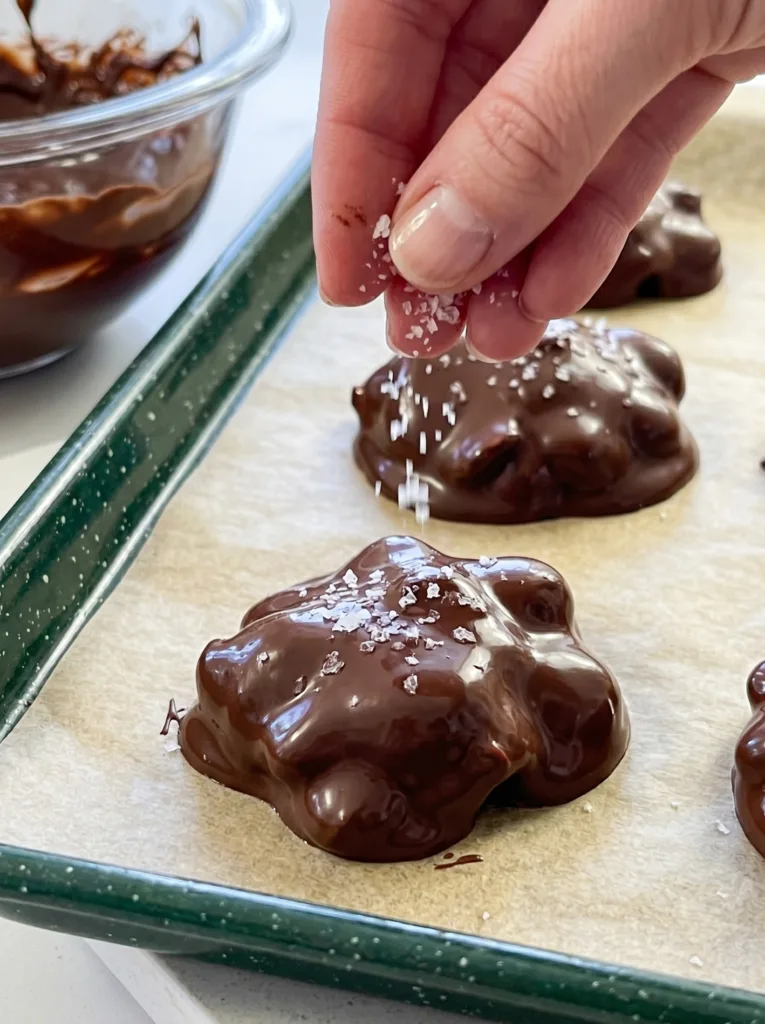 Chocolate covered yogurt clusters with sea salt on parchment ready for freezer