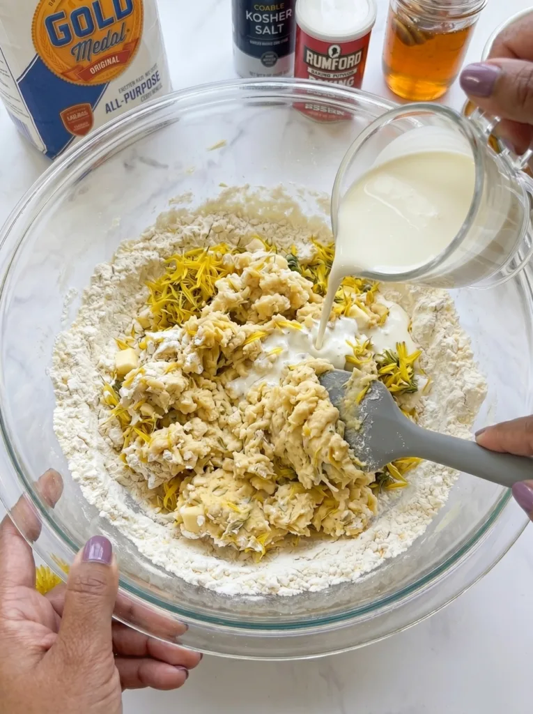Folding fresh dandelion petals and cream into scone dough