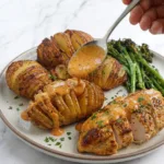 Full plated meal — hasselback potato, creamy Cajun chicken with sauce, and air-fried broccolini on one plate