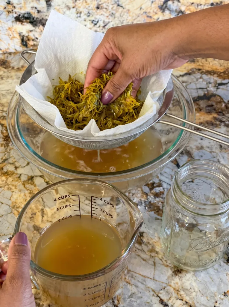 Straining dandelion tea for homemade dandelion jelly — golden liquid