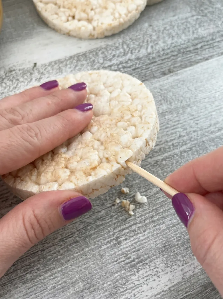 Wooden skewer being inserted into the side of a rice cake. 