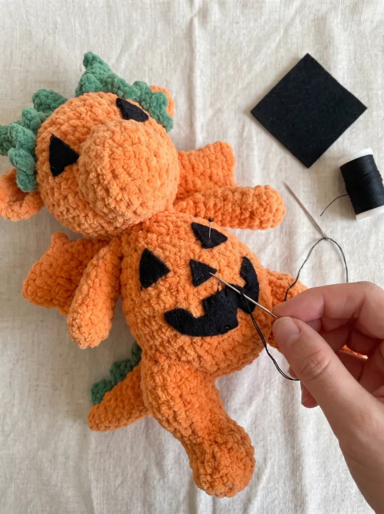 Free Crochet Pumpkin Dragon Pattern (Amigurumi Halloween Dragon) 2 Crochet Pumpkin Dragon felt face with black triangle eyes, nose, and zigzag mouth pinned before sewing
